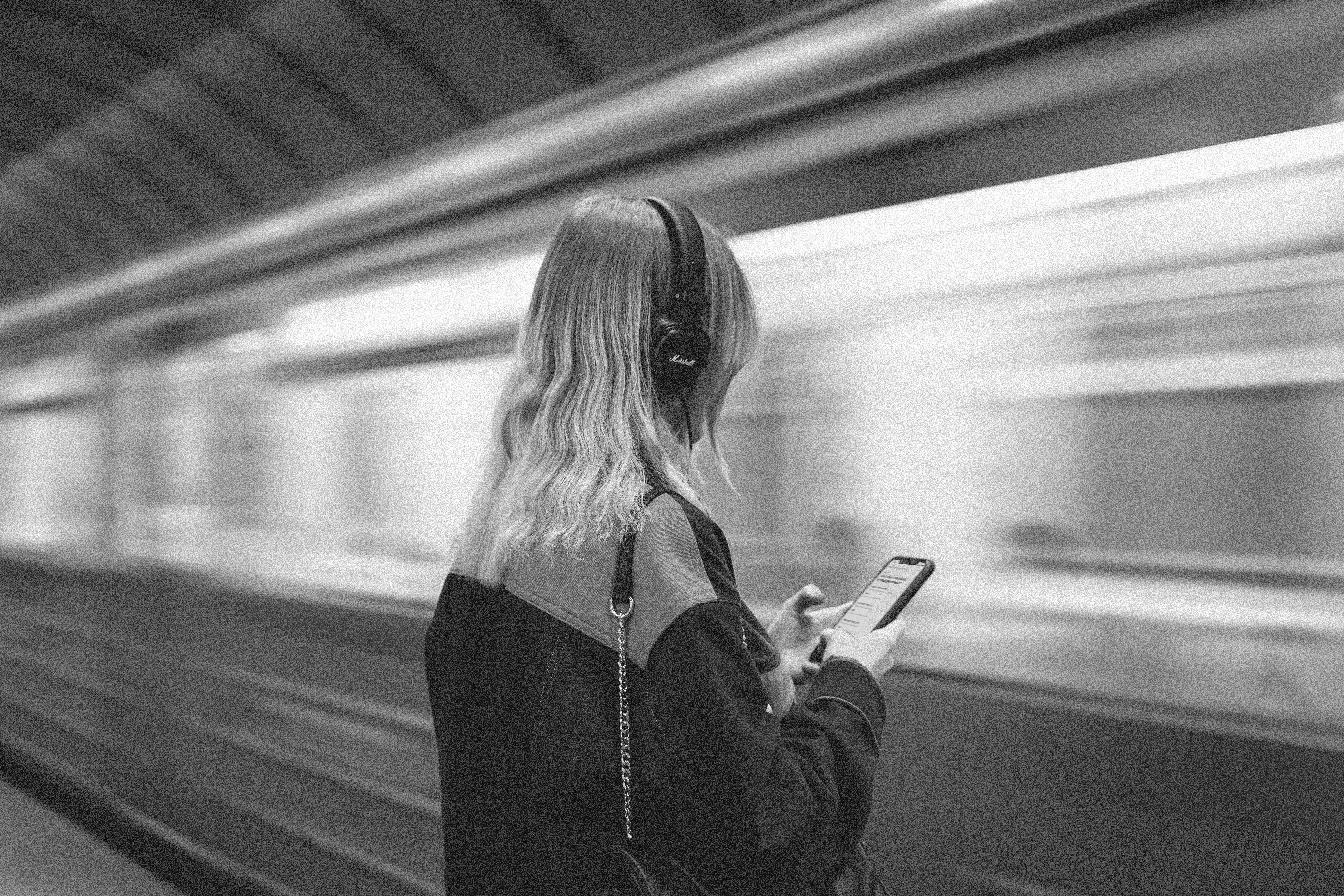 girl with phone infront of a arriving train